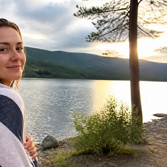 wrapped in a towel by a lake after a swim, hills behind